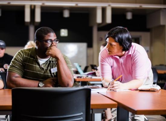 two students discussing academics in a large classroom